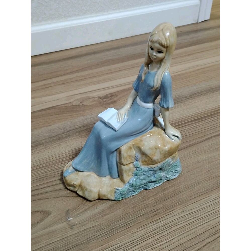 Porcelain figurine posing sitting lady with book sculpture on Rock 5-19-1986